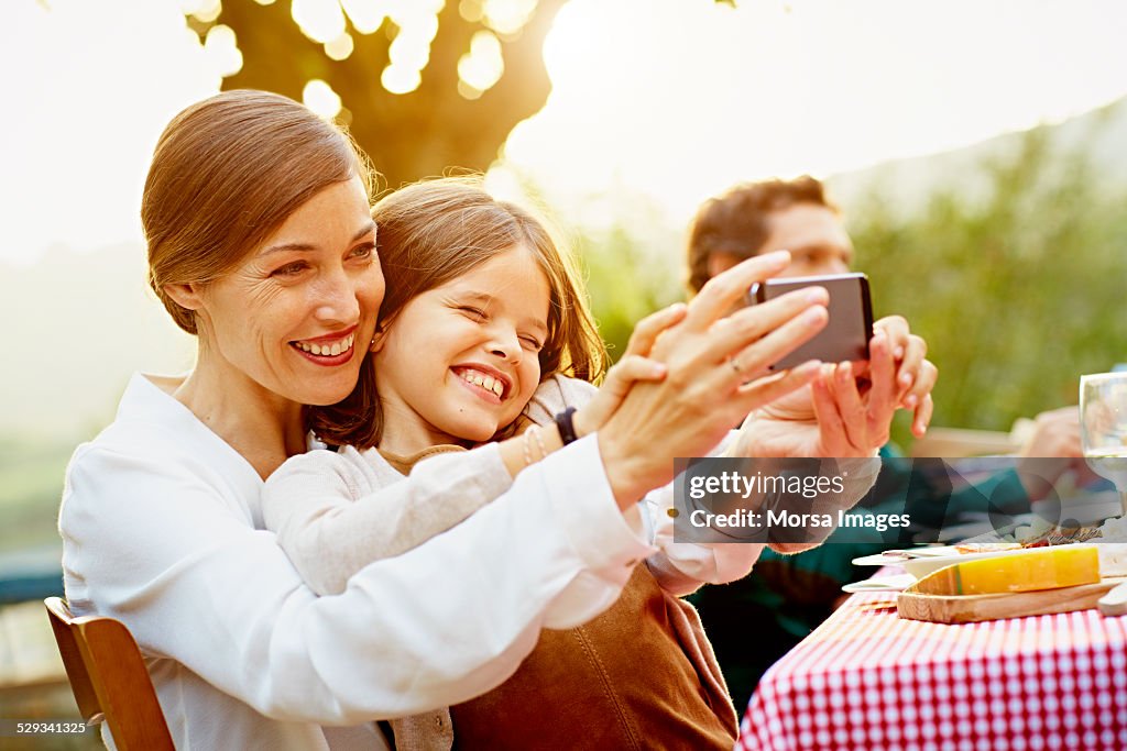 Happy mother and daughter taking selfie in yard