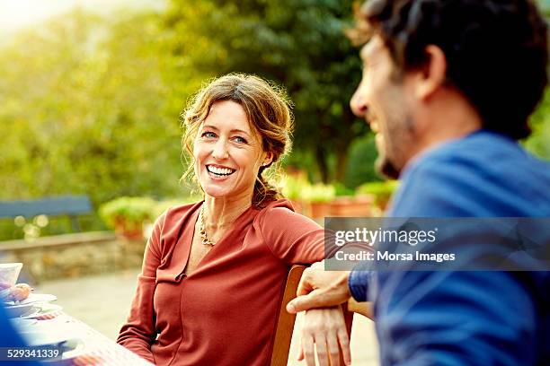 happy woman sitting with man at outdoor table - mature brunette woman stockfoto's en -beelden