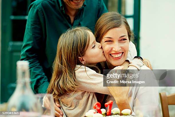 girl kissing mother while celebrating birthday - moment of silence stock-fotos und bilder