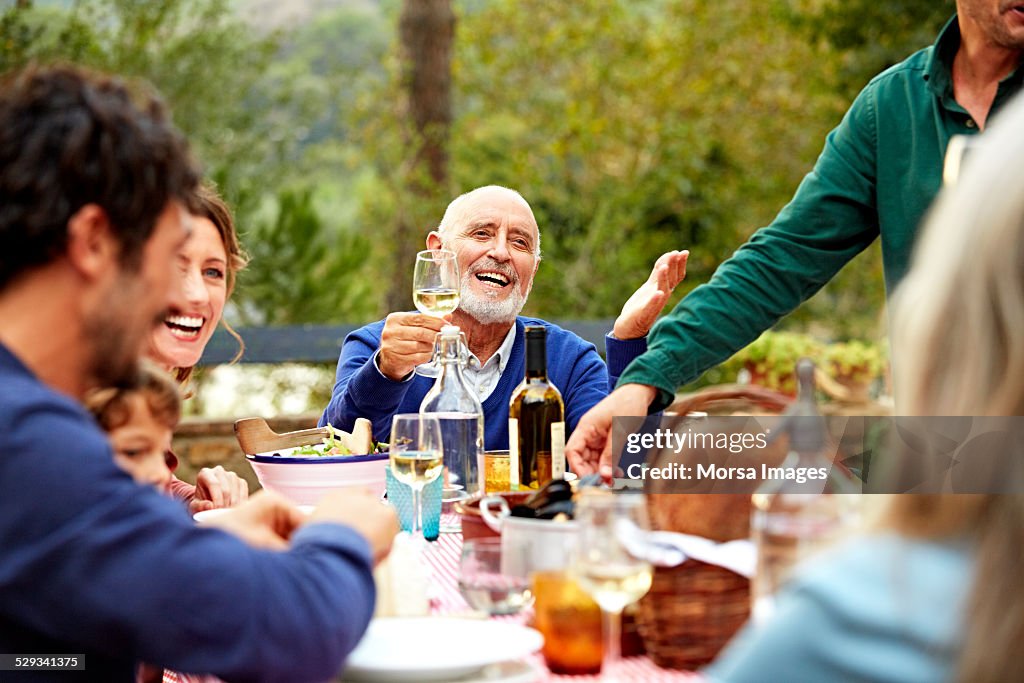 Happy senior man enjoying meal with family in yard