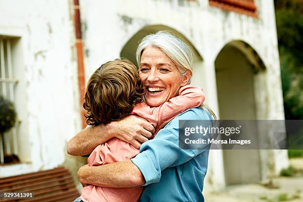 happy grandmother embracing grandson in yard - oma und enkel stock-fotos und bilder