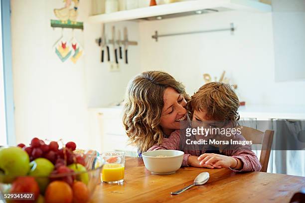 happy mother embracing son having breakfast - son bildbanksfoton och bilder