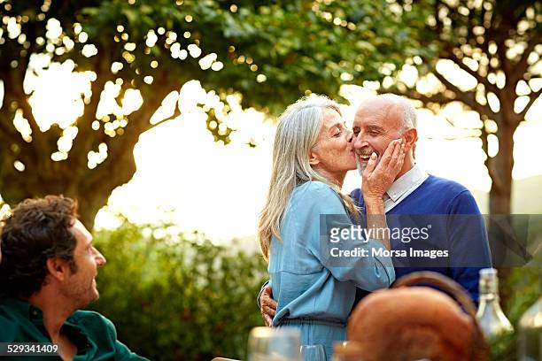 Senior woman kissing man in yard