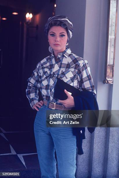 Sylva Koscina in jeans and a plaid shirt with curlers in her hair; circa 1970; New York.