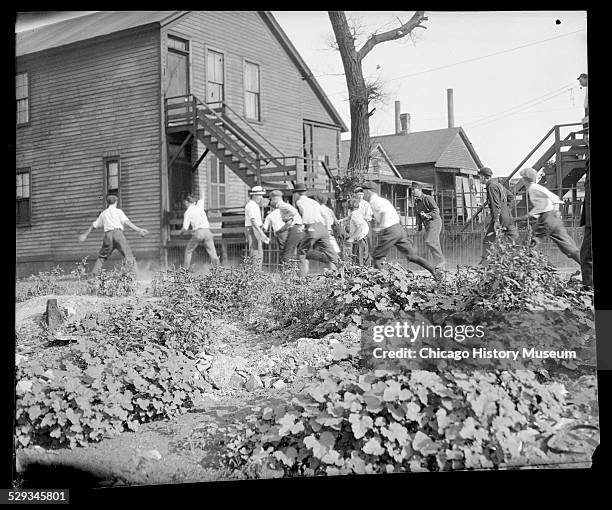 Victim being stoned and bludgeoned under corner of house during the 1919 Chicago Race Riot.