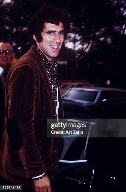 Elliott Gould in a brown velvet jacket getting into a limousine; circa 1970; New York.