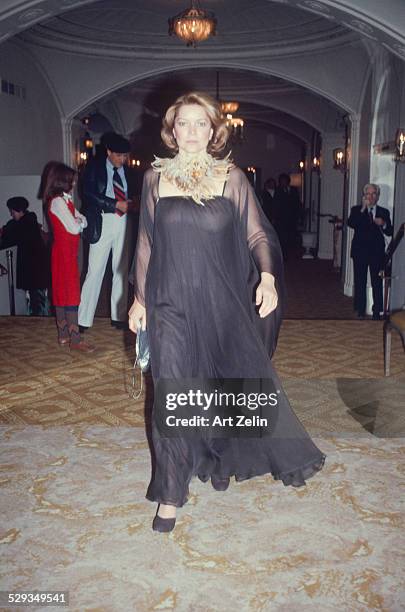 Ellen Burstyn wearing black chiffon with a feather necklace, walking towards the photographer; circa 1970; New York.