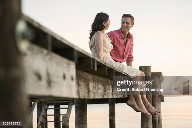 mature couple looking at each other and smiling on pier, bavaria, germany - long jetty stock pictures, royalty-free photos & images