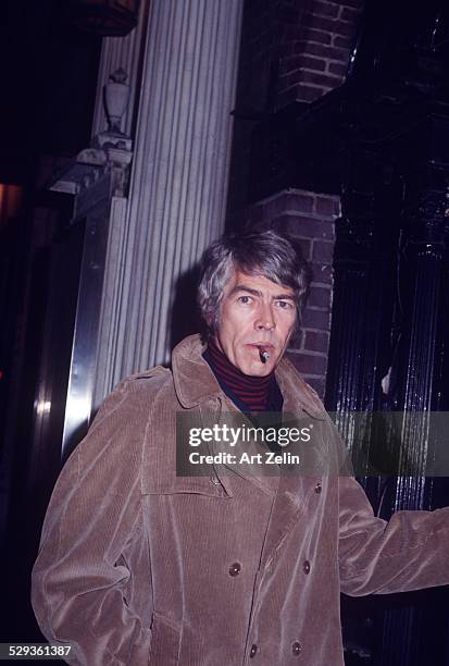 James Coburn in brown over coat smoking a cigar; circa 1970; New York.