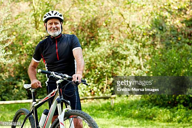 confident senior man with bicycle in park - cycling helmet stock-fotos und bilder