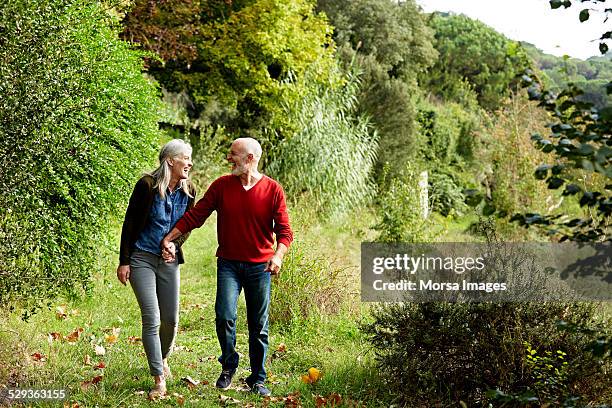 happy senior couple walking in park - 55 59 años fotografías e imágenes de stock