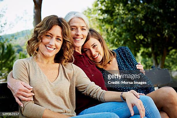 happy family sitting on park bench - nur frauen stock-fotos und bilder