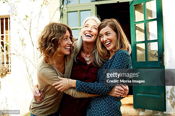 mother and daughters embracing outdoors - lachen stockfoto's en -beelden