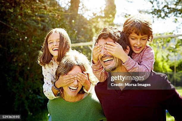 children enjoying piggyback ride on parents - family in the park stock pictures, royalty-free photos & images
