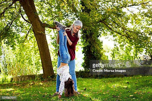 grandmother assisting girl in doing handstand - fare la verticale sulle mani foto e immagini stock