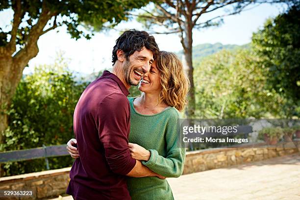 cheerful couple embracing in park - felicidad fotografías e imágenes de stock