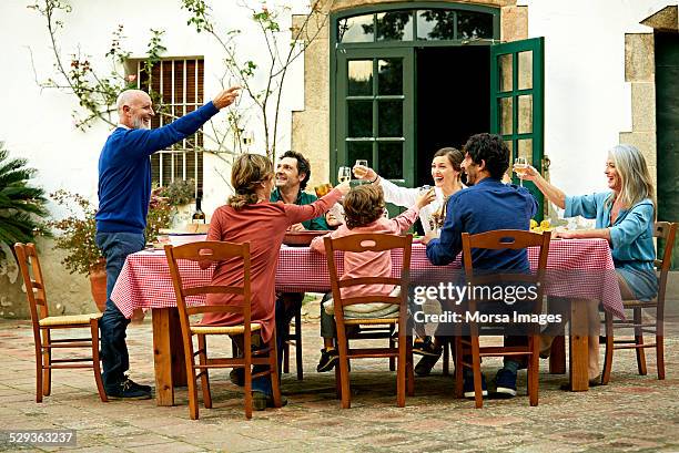 senior man raising toast to family at meal table - prato de comida imagens e fotografias de stock