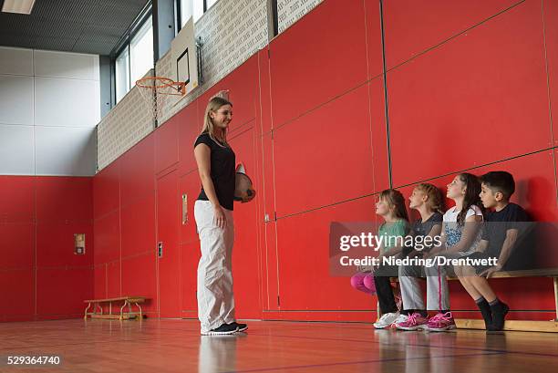 teacher giving advice for group game to children in sports hall, munich, germany, bavaria - kurdish girl - fotografias e filmes do acervo