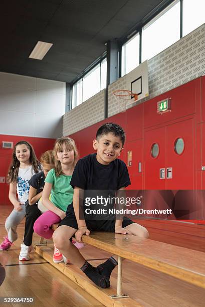 children sitting on bench in sports hall, bavaria, munich, germany - kurdish girl stock pictures, royalty-free photos & images