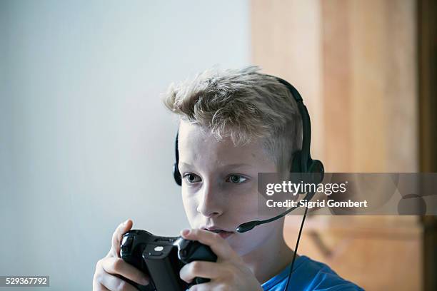 boy wearing headset and playing video game, freiburg im breisgau, baden-w��rttemberg, germany - bambina bionda occhi verdi foto e immagini stock