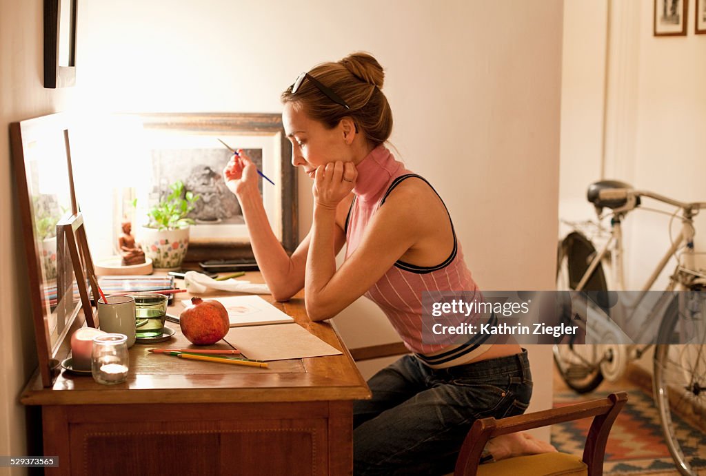 Woman at her desk at home, painting