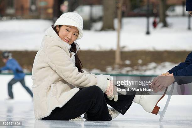 instructor tying shoelace of a woman in an ice rink - boston winter stock pictures, royalty-free photos & images