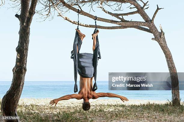young man doing aerial yoga - hang upside down for back stock pictures, royalty-free photos & images