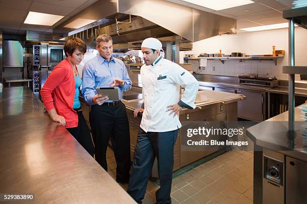 boss and chef looking at tablet pc in restaurant kitchen - restaurant manager - fotografias e filmes do acervo