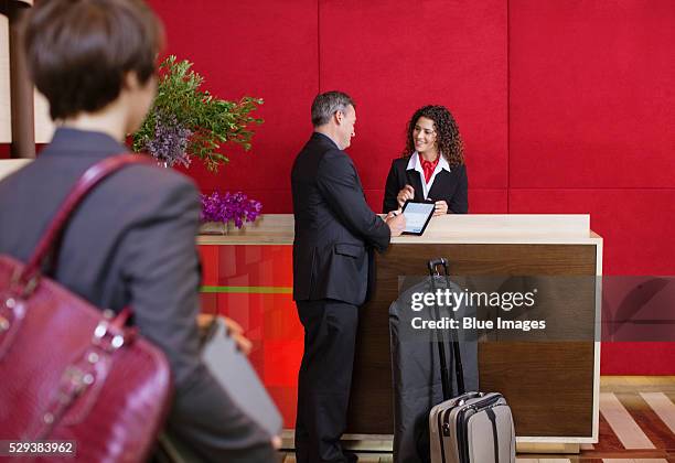 businessman checking in at hotel reception desk - checking in at hotel stock-fotos und bilder