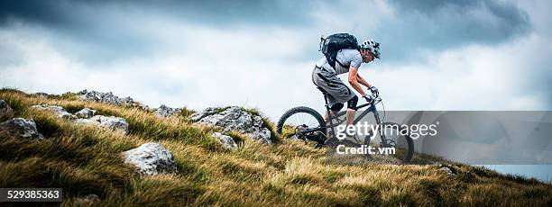 biker riding on a mountain trail - extreme sports bike stock pictures, royalty-free photos & images