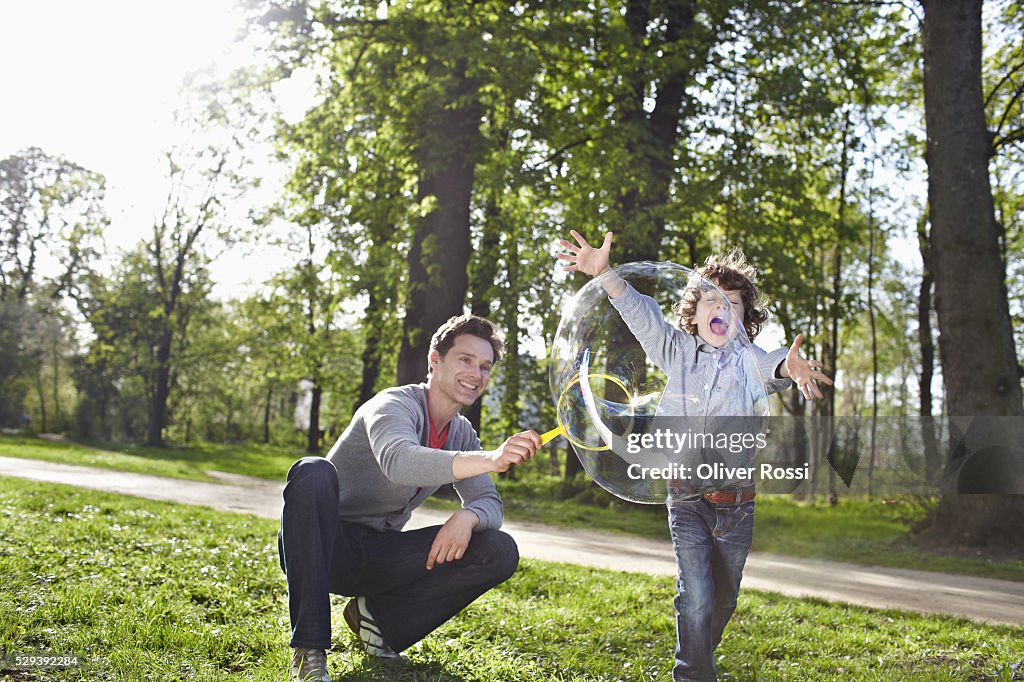 Father and son (7-9) creating bubbles with bubble wand