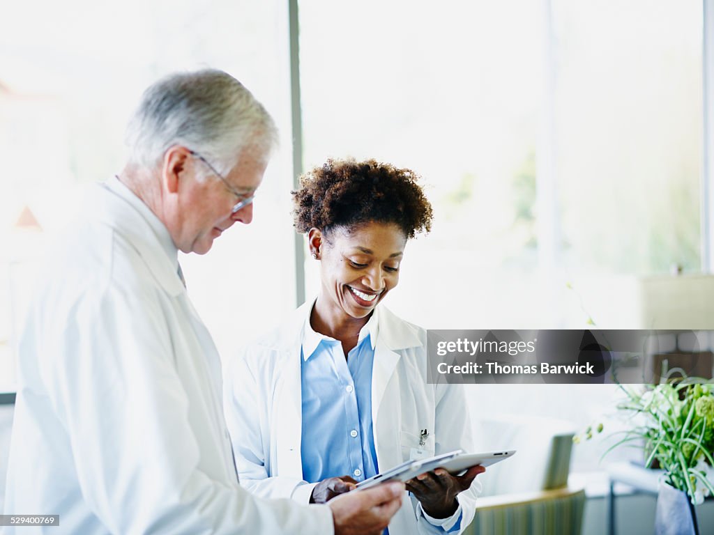 Mature doctors comparing notes on digital tablets