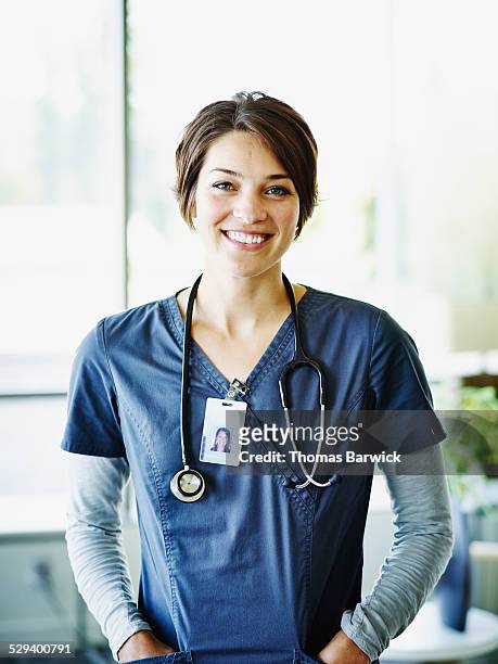 portrait of smiling nurse standing in hospital - frau anfang 30 stock-fotos und bilder