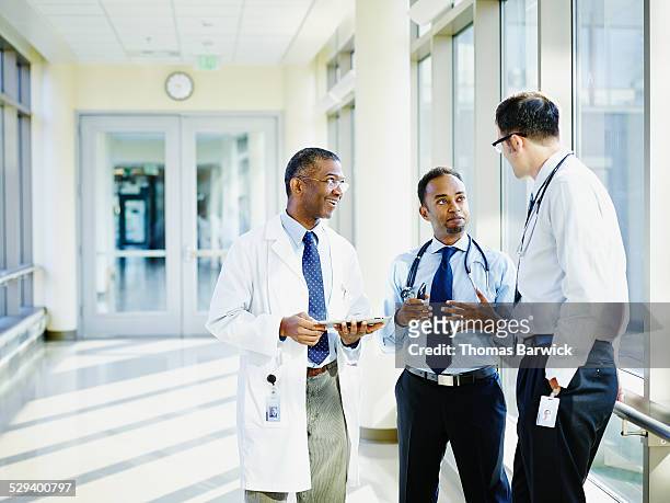 smiling doctors in discussion in hospital - hospital connectivity stockfoto's en -beelden