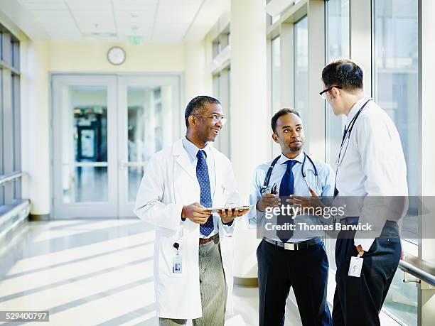 smiling doctors in discussion in hospital - doctor talking imagens e fotografias de stock