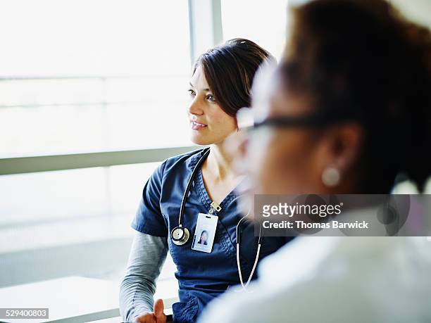 female nurse listening during medical team meeting - differential focus fotografías e imágenes de stock