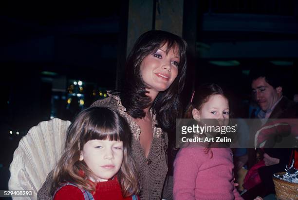 Jaclyn Smith with 2 little girls wearing a taupe sweater; circa 1970; New York.