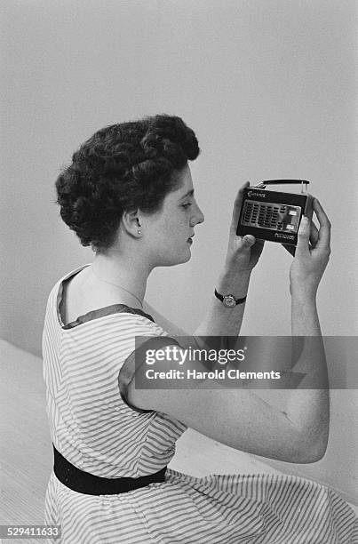 Woman displays a pocket size radio at the Radio Show exhibition, 26th August 1958.