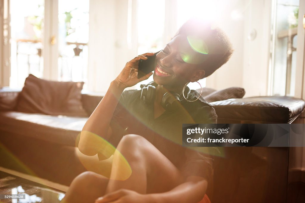Afro mulher falando no telefone, na sala de estar