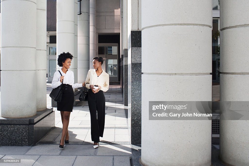 Two business woman walking together outside.