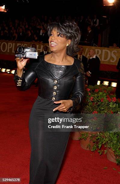 Oprah Winfrey films the crowd as she arrives at the 30th Annual People's Choice Awards.