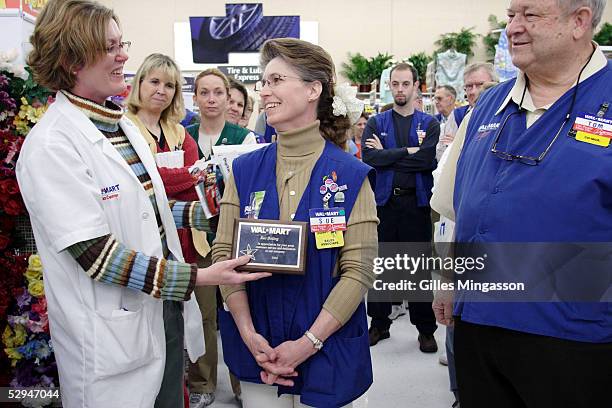 Wal-Mart employee is congratulated by her store manager after receiving a plaque as reward, a common practice in the company, March 16, 2005 in...