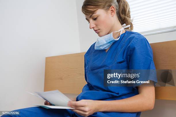 doctor reading paperwork - surgical mask profile stock pictures, royalty-free photos & images