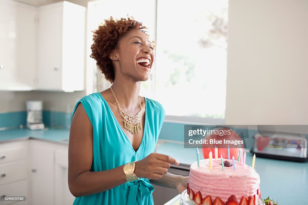 Laughing woman preparing birthday cake