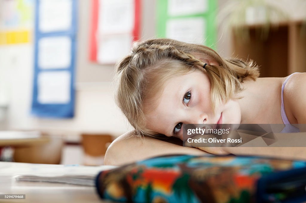 Girl resting on desk in classroom