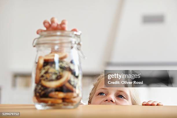 girl reaching for cookie jar - cookie jar stock-fotos und bilder