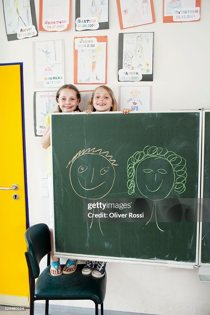 Girls behind blackboard in classroom