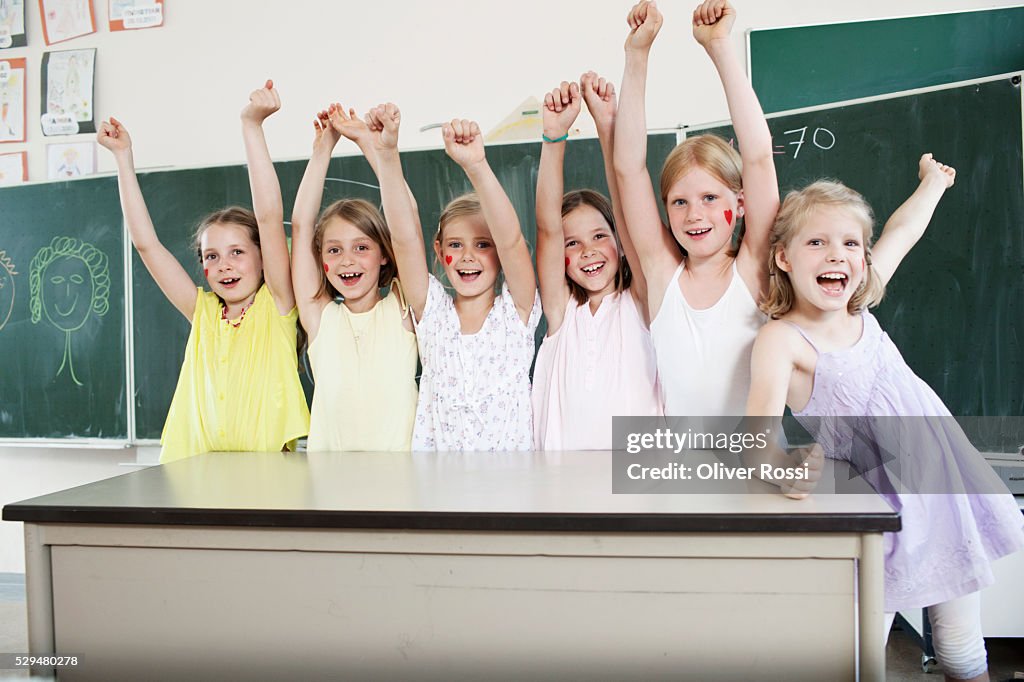Children with arms raised in classroom