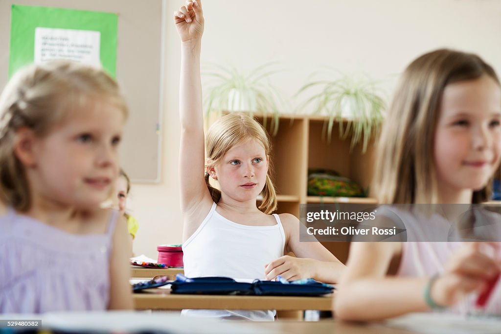 Girl raising hands in classroom