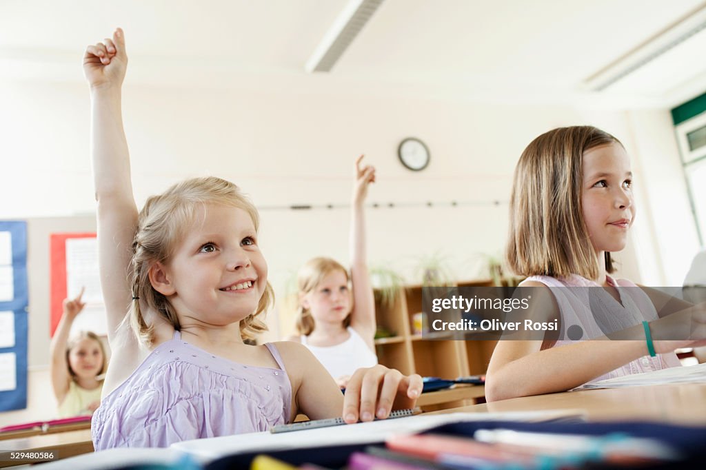 Children raising hands in classroom